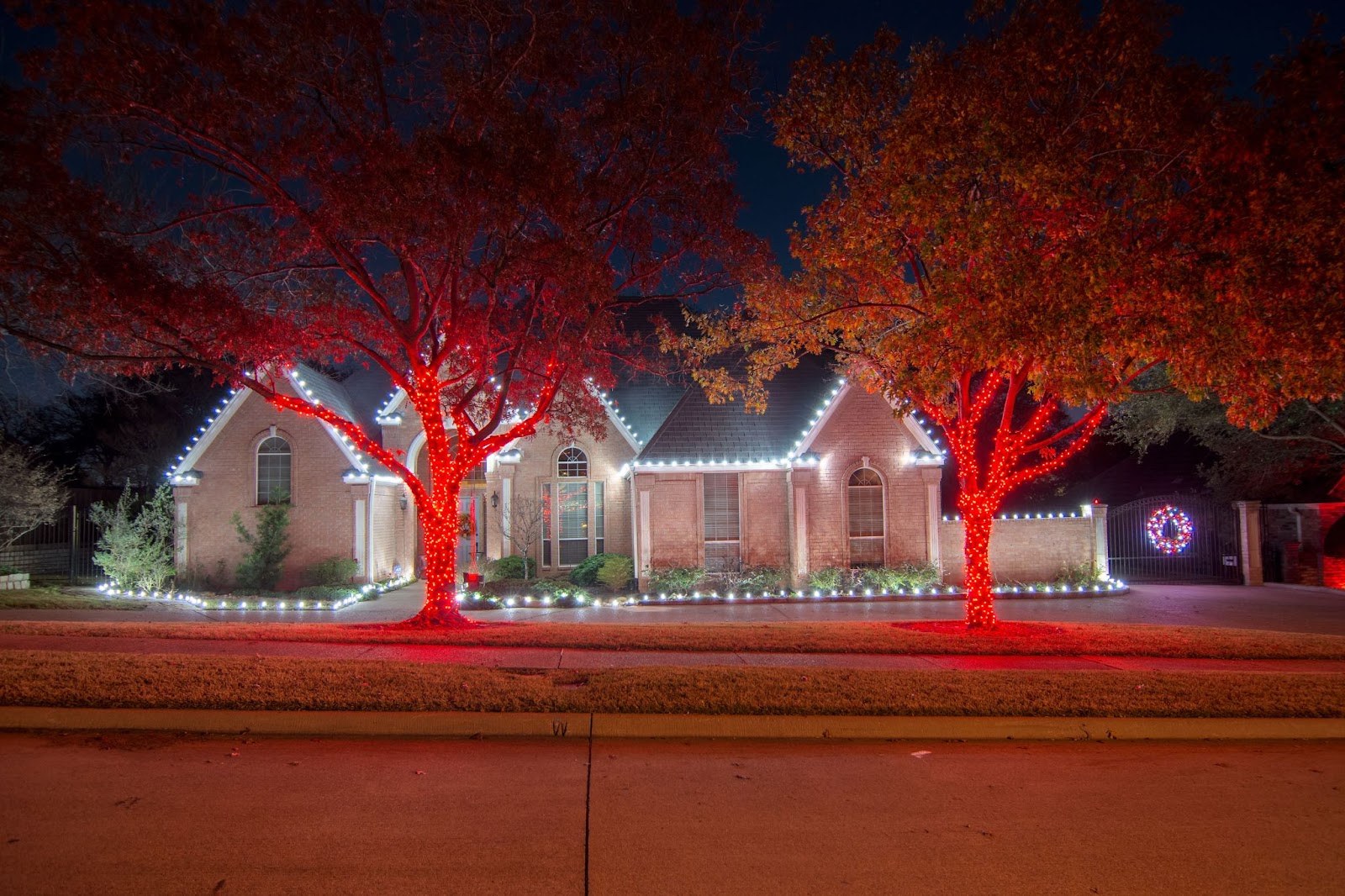 Walkway lined with warm holiday lighting leading to a decorated home